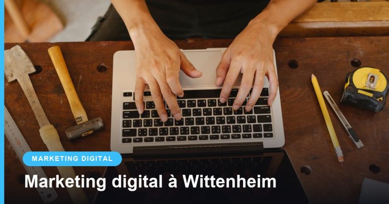 Mains d'un artisan tapant sur un ordinateur portable posé sur un établi avec ses outils
