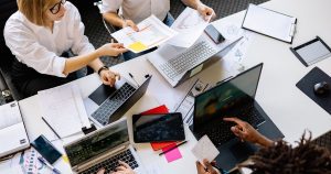 Vue de dessus d'une équipe travaillant ensemble sur des documents et des ordinateurs portables