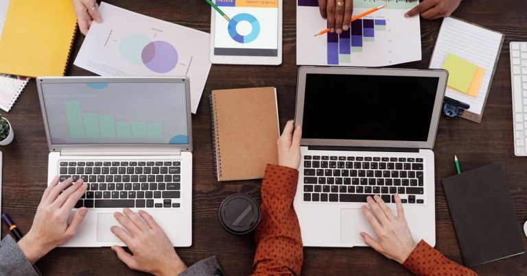 Vue de dessus d'une équipe travaillant sur une stratégie marketing avec ordinateurs et graphiques