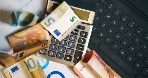 Billets en euros, calculatrice et clavier sur un bureau pour estimer un budget