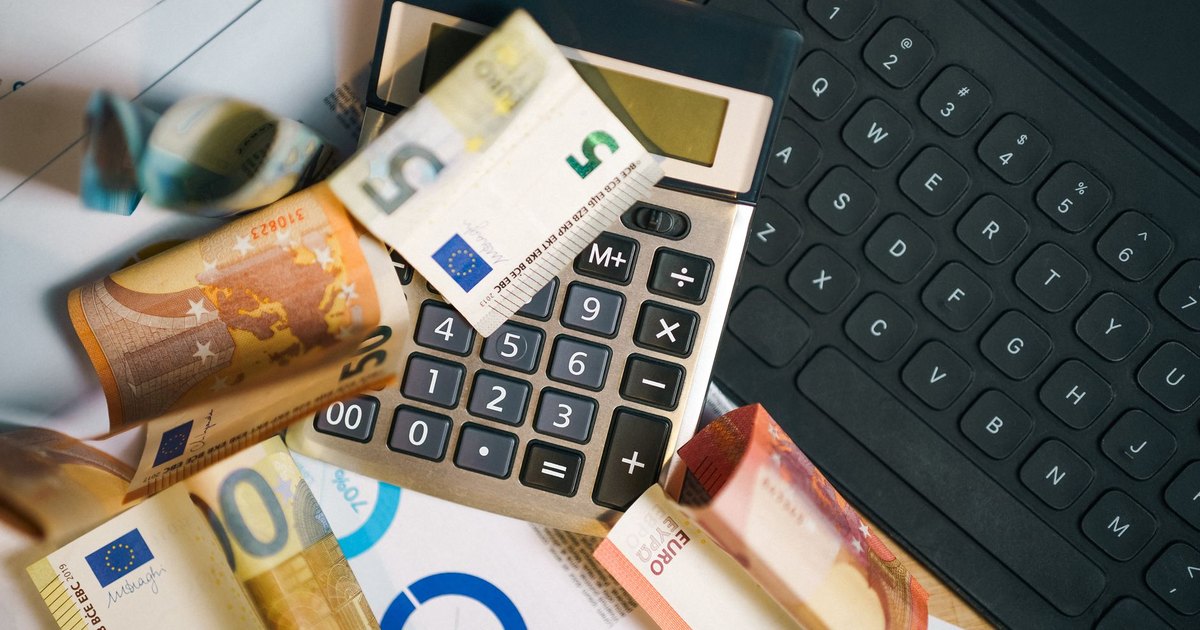 Billets en euros, calculatrice et clavier sur un bureau pour estimer un budget