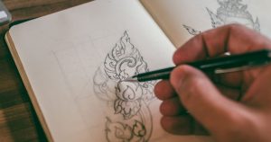 Main dessinant un motif détaillé dans un carnet de croquis