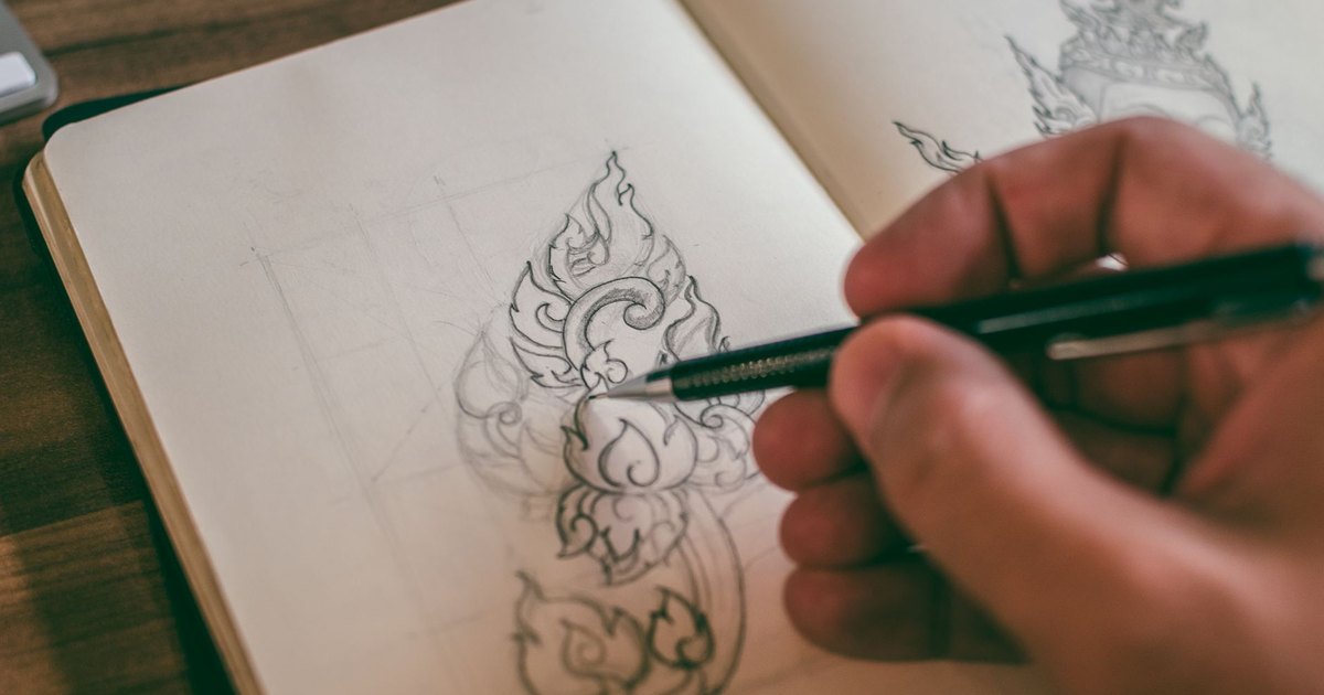 Main dessinant un motif détaillé dans un carnet de croquis