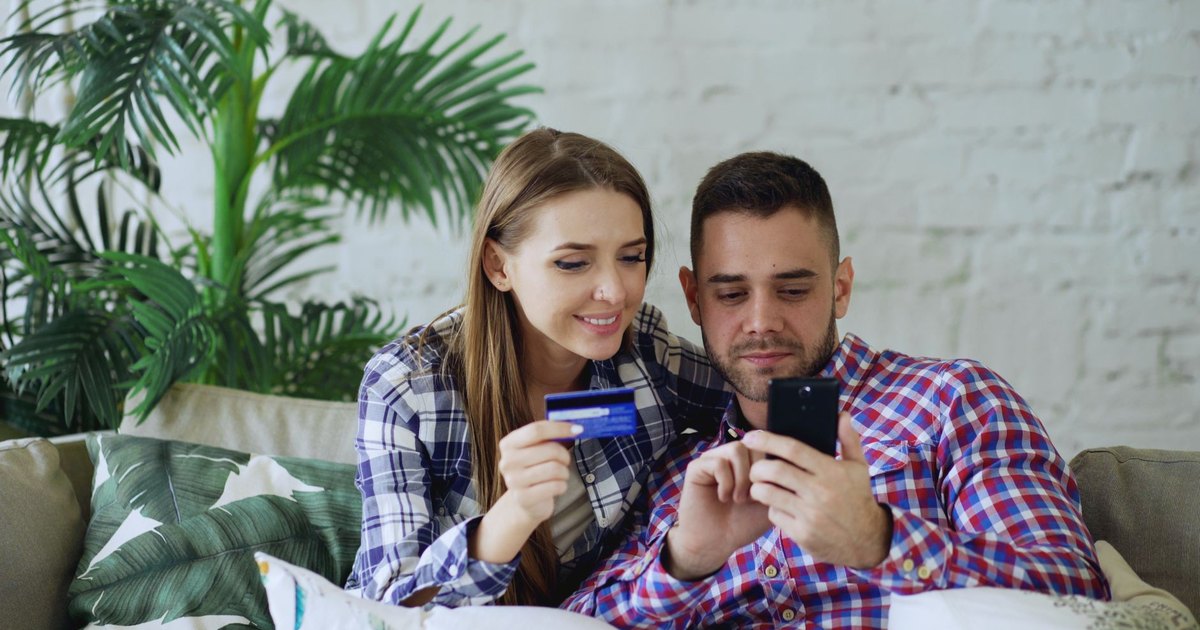 Couple souriant faisant un achat en ligne sur smartphone