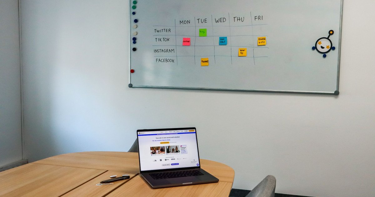 Salle de réunion avec ordinateur portable et planning sur tableau blanc
