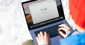 Mains tapant sur un ordinateur portable ouvert sur la page d'accueil de Google