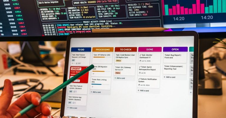 Tableau de suivi de tâches sur tablette devant des écrans d'indicateurs