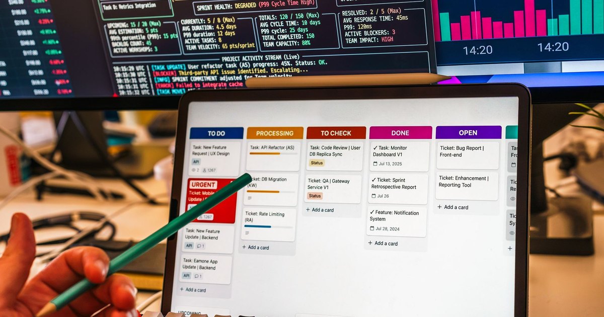 Tableau de suivi de tâches sur tablette devant des écrans d'indicateurs