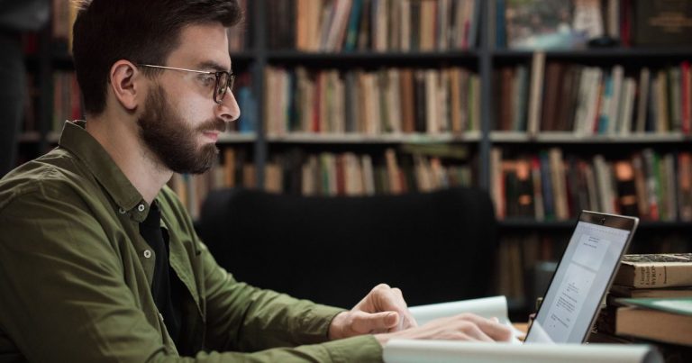 Homme travaillant sur un ordinateur portable dans une bibliothèque