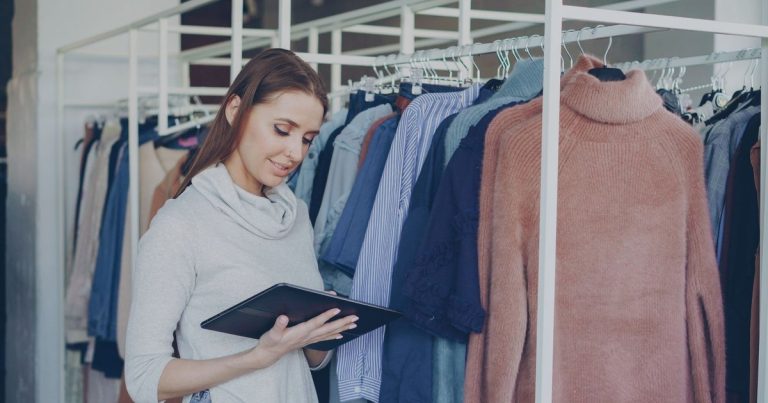 Vendeuse gérant le stock d'une boutique de vêtements sur une tablette