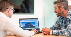 Deux professionnels discutant d'un projet de bâtiment affiché sur un ordinateur portable