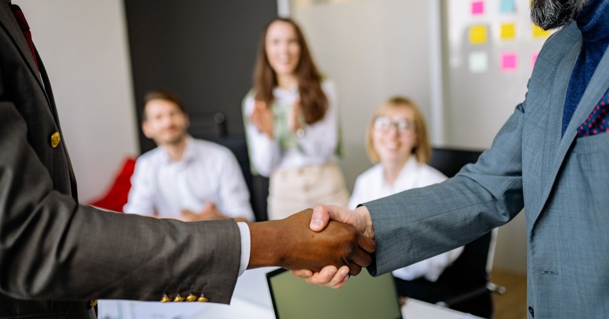 Poignée de main entre professionnels devant une équipe dans un bureau