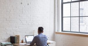 Homme travaillant sur ordinateur portable dans un bureau à domicile lumineux