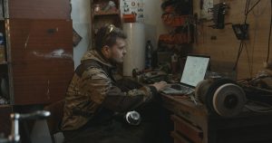 Homme utilisant un ordinateur portable dans un atelier entouré d'outils