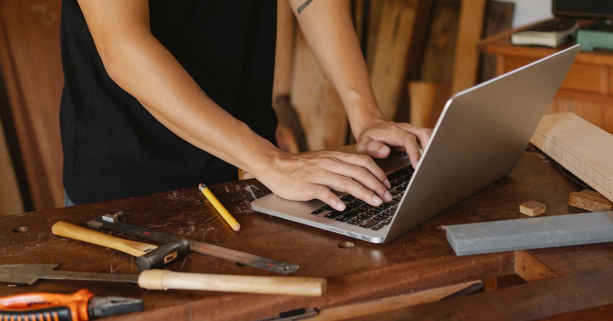 Artisan consultant internet sur un ordinateur portable parmi ses outils de menuiserie