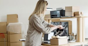 Femme emballant une commande dans son espace de vente en ligne