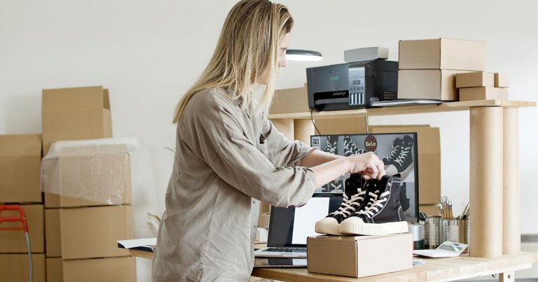 Femme emballant une commande dans son espace de vente en ligne