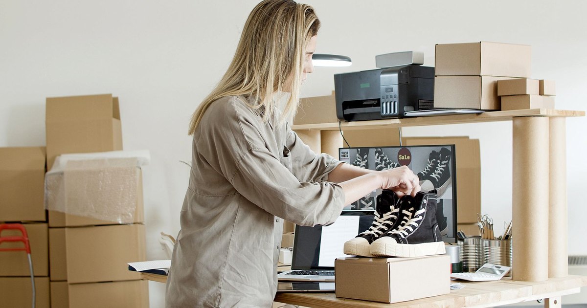 Femme emballant une commande dans son espace de vente en ligne