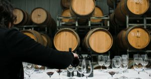 Sommelier servant du vin dans une cave devant des tonneaux