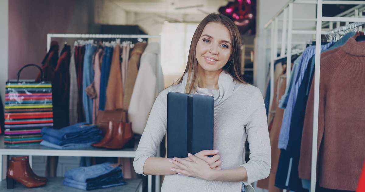 Commerçante souriante tenant une tablette dans sa boutique de vêtements