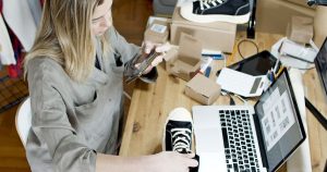Femme photographiant des chaussures à vendre en ligne dans son espace de travail