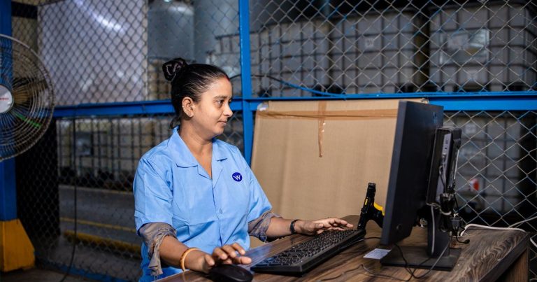 Employée d'un site industriel travaillant sur un ordinateur dans l'entrepôt