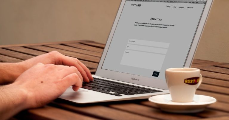 Mains tapant sur un ordinateur portable à côté d'une tasse de café