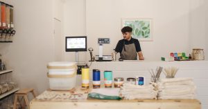 Commerçant derrière le comptoir de sa petite boutique avec un écran d’encaissement