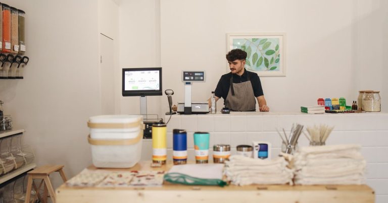 Commerçant derrière le comptoir de sa petite boutique avec un écran d’encaissement