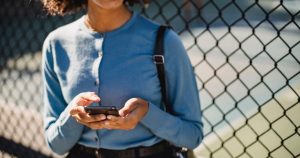 Femme souriante utilisant son smartphone en extérieur