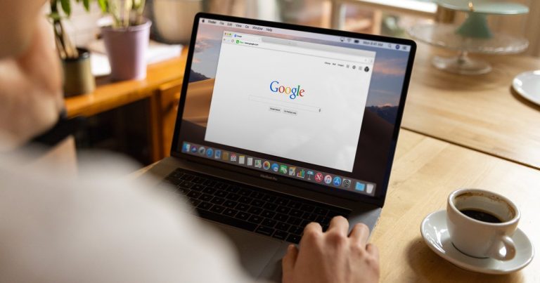 Personne consultant Google sur un ordinateur portable à côté d'une tasse de café