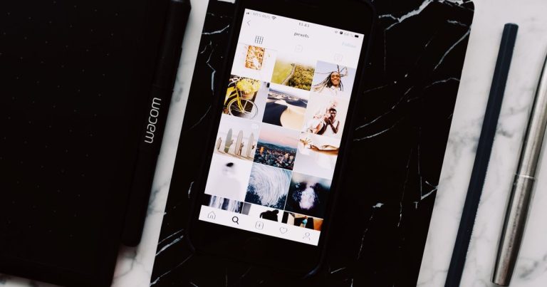 Carnet noir et smartphone affichant des photos sur une table en marbre