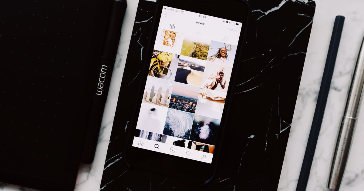 Carnet noir et smartphone affichant des photos sur une table en marbre