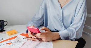 Femme calculant un budget avec une calculatrice entourée de factures